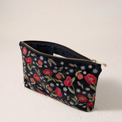 Poppy Meadow velvet everyday pouch in black featuring red poppy and blue floral embroidery with a gold zip fastening.