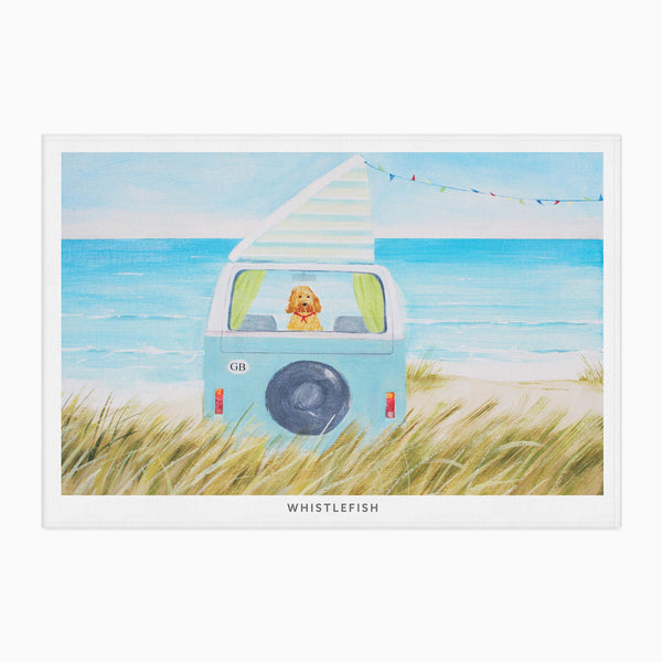 Hannah Cole Camper Dogs tea towel featuring a golden dog in a blue camper van on a sandy beach by the sea.