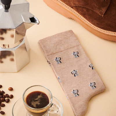 The Barista Beige socks in a soft tan colour featuring a repeating pattern of small silver coffee moka pots.