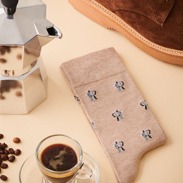 The Barista Beige socks in a soft tan colour featuring a repeating pattern of small silver coffee moka pots.