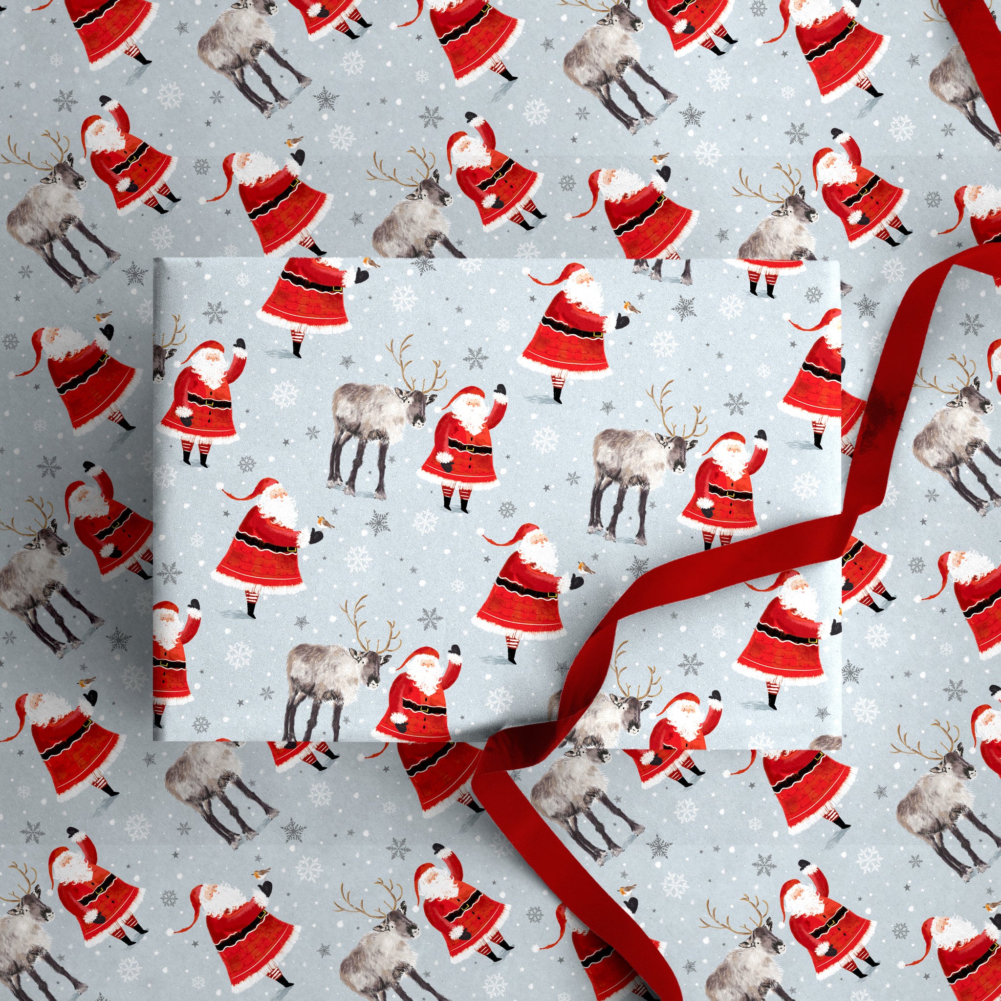 Santa & Reindeers Christmas wrapping paper featuring a festive pattern of Santa Claus and reindeer on a pale blue background.