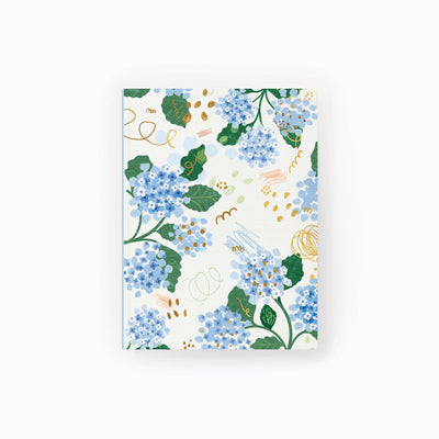 Hydrangea Notebook featuring a floral pattern of blue hydrangea flowers, green leaves, and gold abstract scribbles.