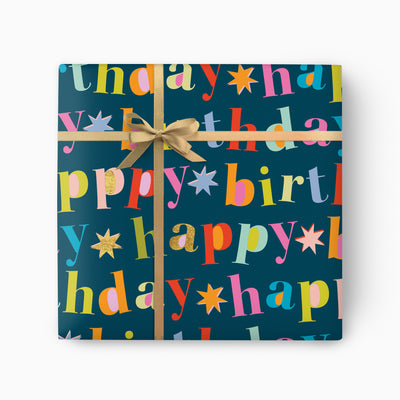 Bold Navy Birthday Wrapping Paper featuring colourful Happy Birthday text and star motifs, tied with a gold ribbon.