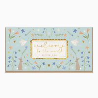 Bunnies & Birds New Baby Card featuring rabbits, birds, and flowers on a pale blue background with welcome to the world text.