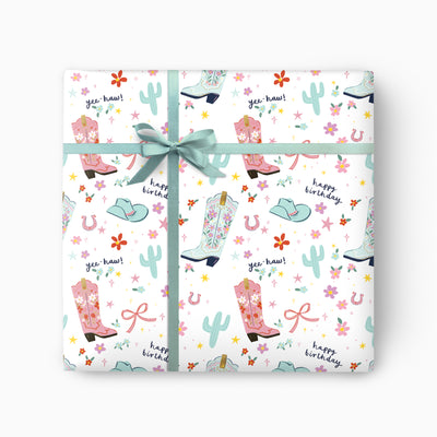 Cowboy Fun wrapping paper featuring pink and blue cowboy boots, cacti, and flowers with a sage green ribbon bow.