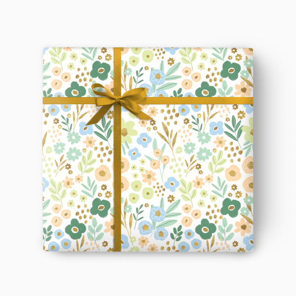 Meadow Bloom wrapping paper featuring a floral pattern in soft blue, green, and peach, tied with a gold ribbon.