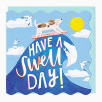 Have A Swell Day birthday card featuring a dog surfing on a blue wave, with seagulls, a yellow sun, and a scalloped edge.