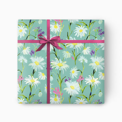 Messy Daisy wrapping paper featuring white flowers on a teal background, tied with a dark pink ribbon and bow.