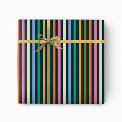 Party Stripes wrapping paper featuring colourful vertical stripes tied with a gold ribbon and bow.