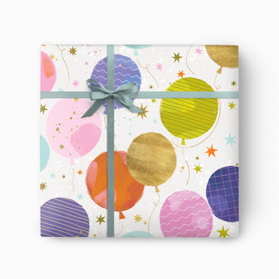 Pink Balloon Wrapping Paper featuring colourful patterned balloons and gold stars, tied with a sage green ribbon bow.