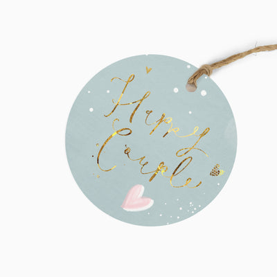 Round Pop & Sparkle gift tag in pale blue with Happy Couple text, a pink heart, and a rustic twine tie.