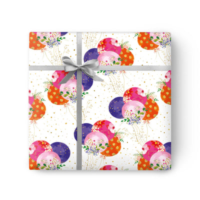 Pretty Balloons wrapping paper featuring colourful floral balloons and gold dots, tied with a grey ribbon.