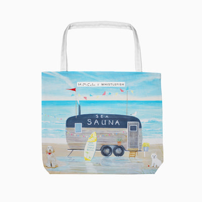Sea Sauna Tote Bag featuring a beach scene with a wooden sauna caravan, surfboard, bunting, and two dogs on the sand.
