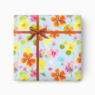 Sky Bloom wrapping paper featuring a colourful watercolour floral pattern on a light blue background with a brown ribbon.
