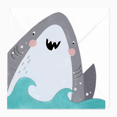 Stevie The Shark cut-out greeting card featuring a grey shark with pink cheeks in turquoise waves against a white envelope.
