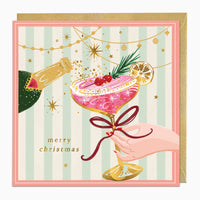 Vintage Champagne Christmas card featuring a hand holding a pink cocktail, gold stars, and bunting on a striped background.